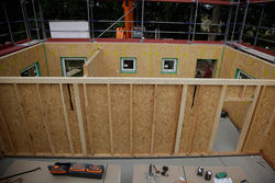 01 MG 2873 web.jpg PLY Kennzeichen des Holzrahmenbaus: das Ständerwerk oder auch Skelett genannt, aus vertikalen Holzständern, welche hier bereits beplankt sind.